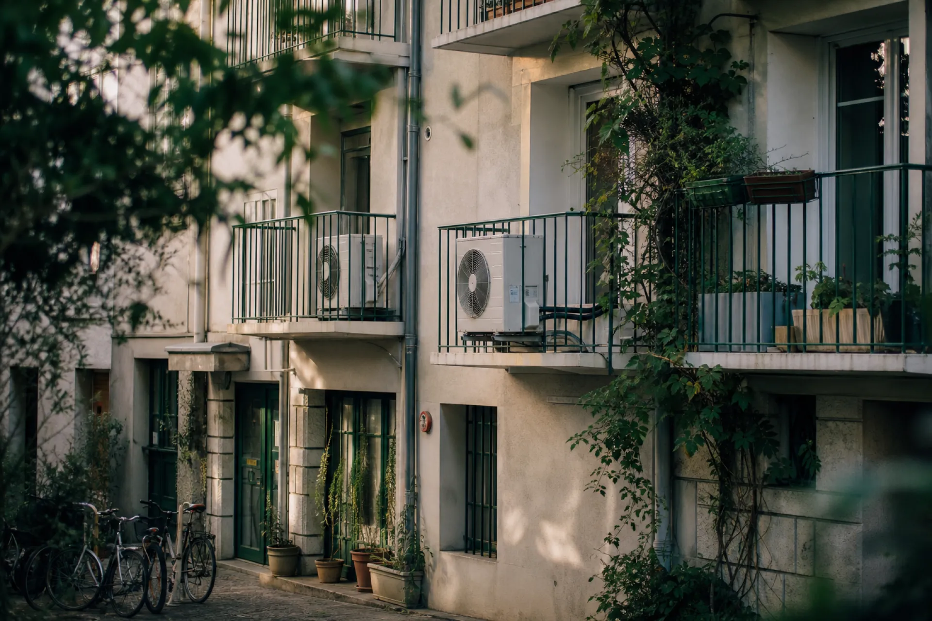 Cour d'un petit immeuble avec des unités de climatisation et de pompe à chaleur fixées aux balcons